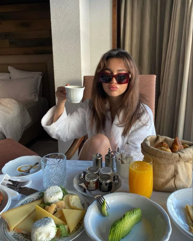 a woman sitting at a table with food and drinks