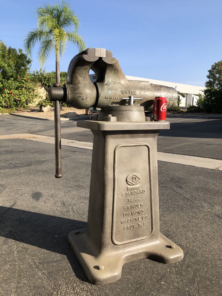 a large metal object sitting on the side of a road next to a palm tree