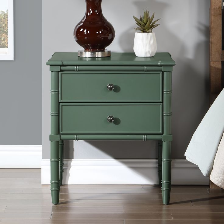 a green table with two drawers and a vase on top