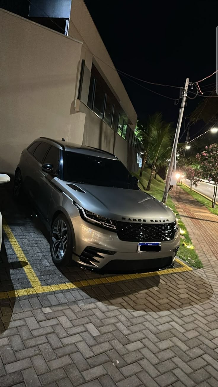 two cars parked next to each other in front of a building at night with lights on