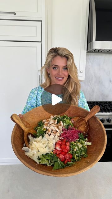 a woman holding a wooden bowl filled with salad