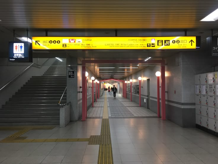 an empty subway station with stairs leading up to the exit door and people walking down