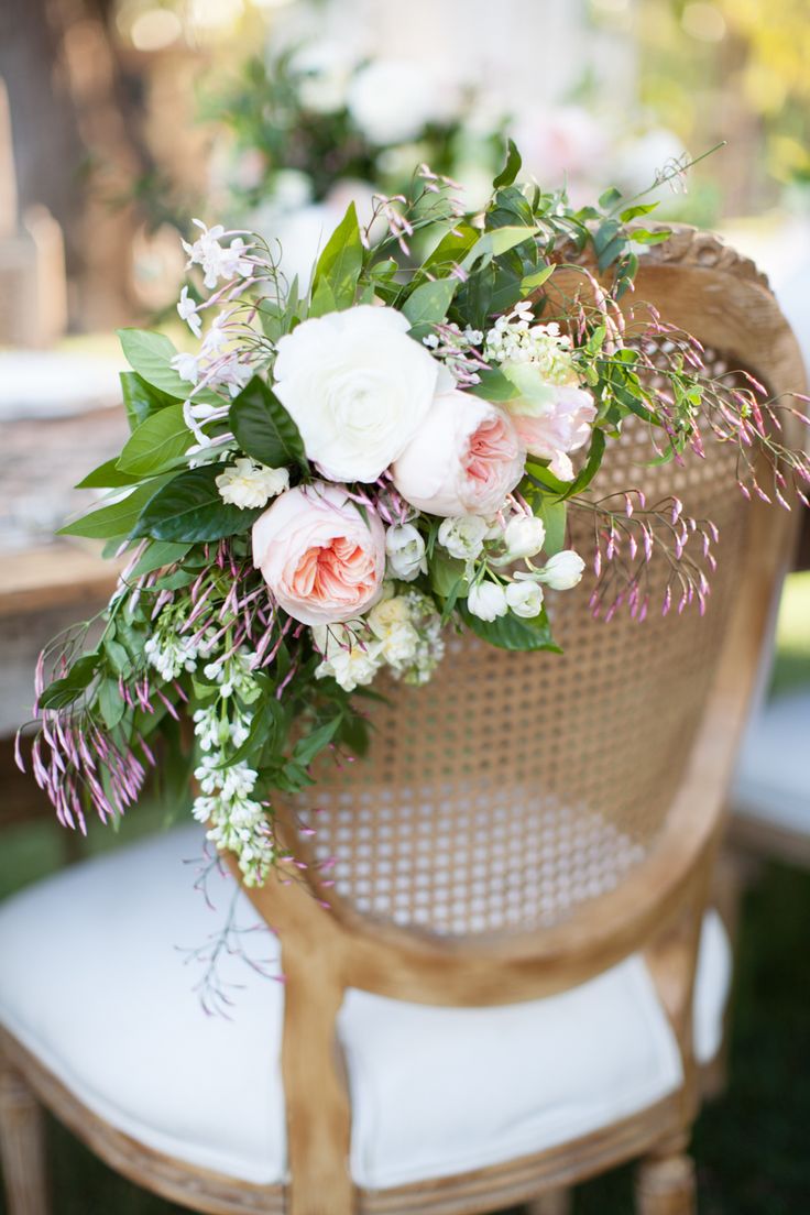 a bouquet of flowers is sitting on top of a wicker chair at an outdoor dinner table