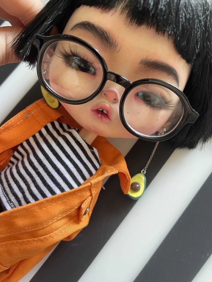 a close up of a doll with glasses on it's face and black hair