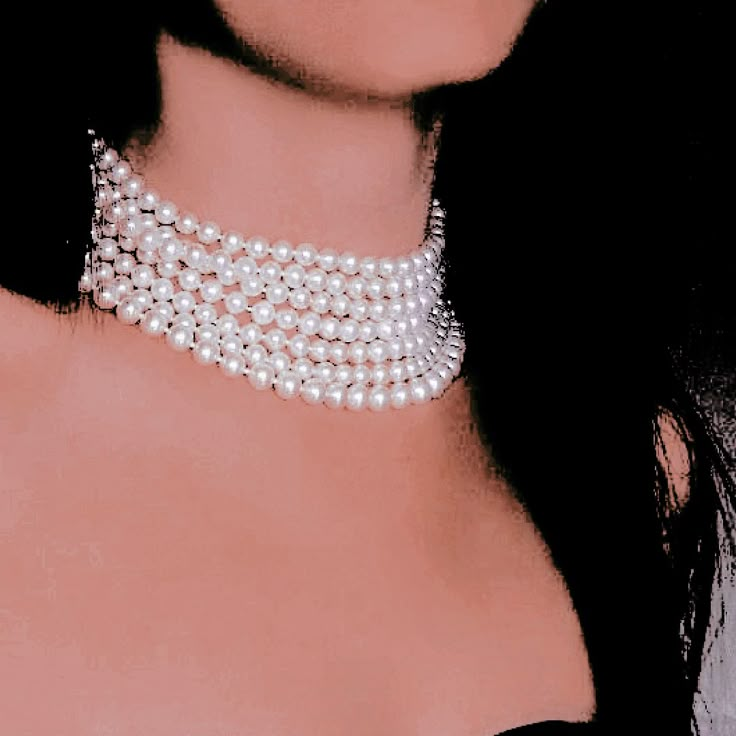 a close up of a woman wearing a necklace with pearls on it's neck