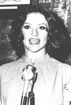 an old photo of a woman holding a microphone and making a face with her eyes wide open