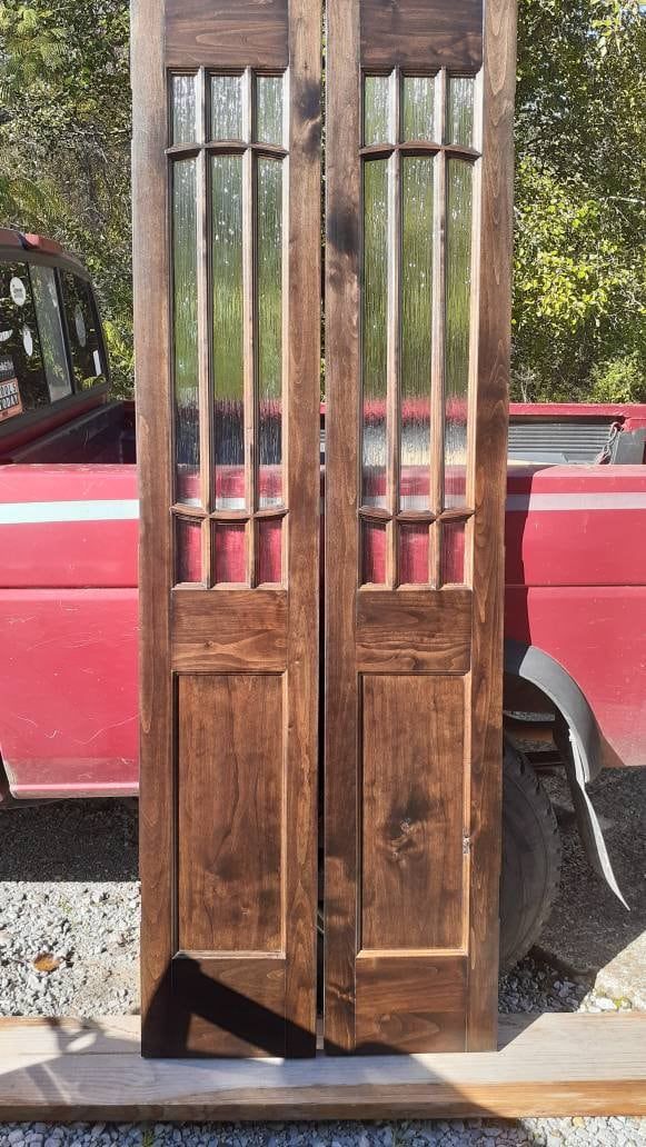 two wooden doors sitting next to each other in front of a red truck with the door open