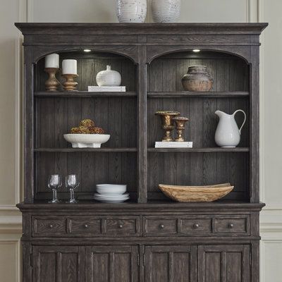 an old fashioned wooden china cabinet with glass doors and shelves on the top, in a living room