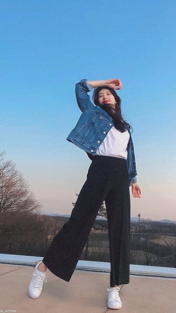 a woman in white shirt and black pants posing for the camera with her hands behind her head