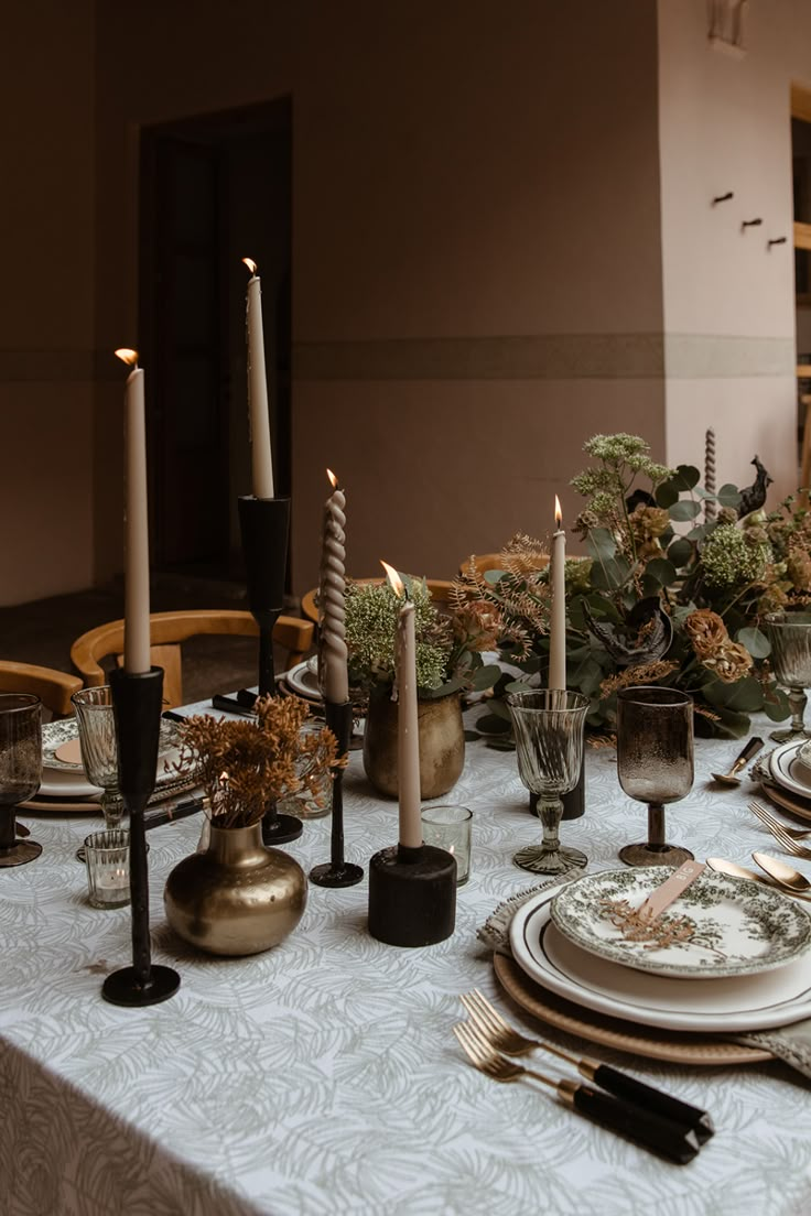 the table is set with candles, plates and silverware for an elegant dinner party