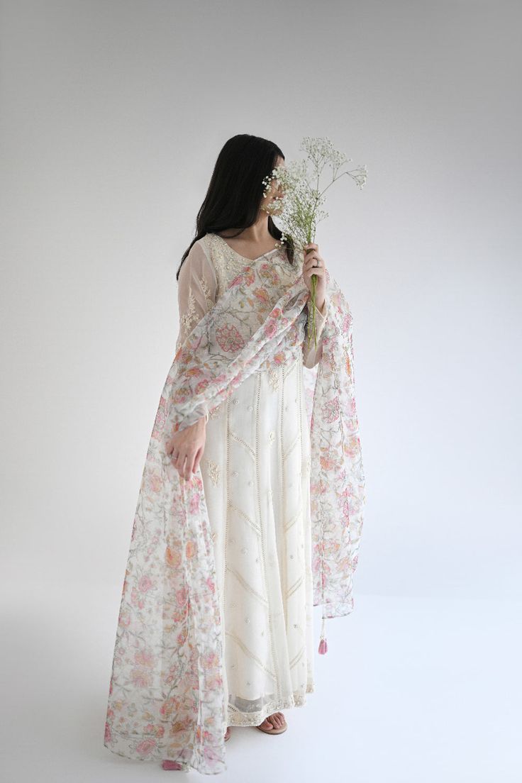 Curated on the softest luxurious pure ivory organza, featuring hand ivory embroidery with clusters of pearls and crochet laces. Styled with a printed organza dupatta and matching trousers. The length of this stunning kalidaar is 50 inches. Order Duration: 4 to 6 weeks White Chanderi Sharara With Dupatta, White Silk Anarkali Set For Eid, Eid White Silk Anarkali Set, Designer White Palazzo Set With Dupatta, White Anarkali Set With Sheer Dupatta, Cream Anarkali Set With Floral Embroidery, Festive Organza Palazzo Set With Floral Embroidery, Off White Silk Anarkali Set With Dupatta, White Palazzo Set With Dupatta In Saree Style