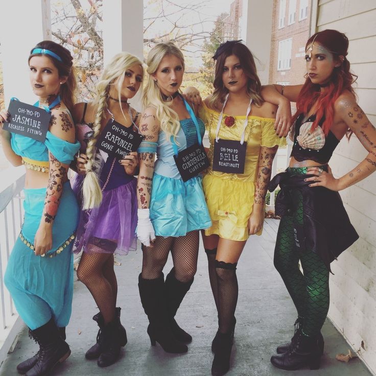 four women dressed up in costumes posing for the camera with signs on their shoulders and legs