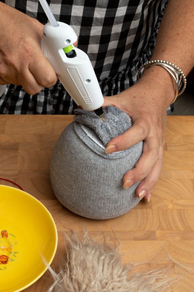 a person using a hair dryer on top of a yellow bowl next to a cat