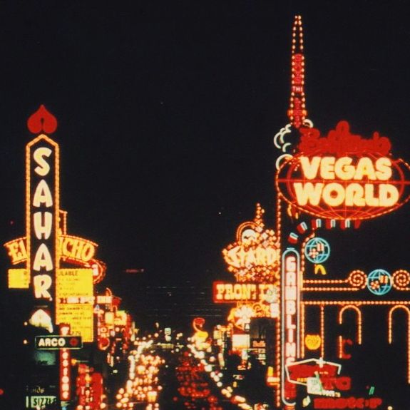 the las vegas world sign is lit up at night with neon lights and buildings in the background