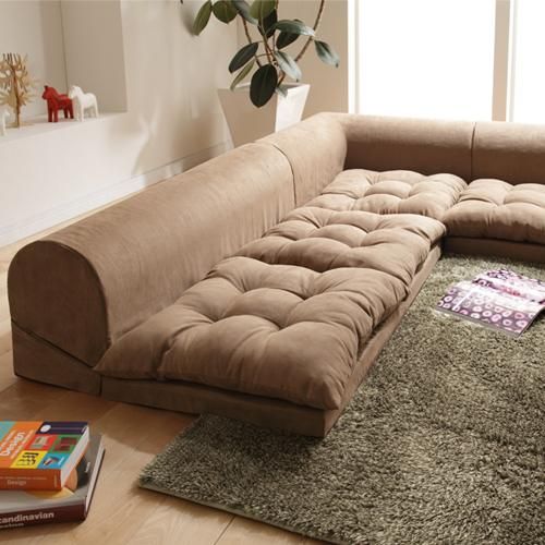 a couch sitting on top of a wooden floor next to a white bath tub in a bathroom