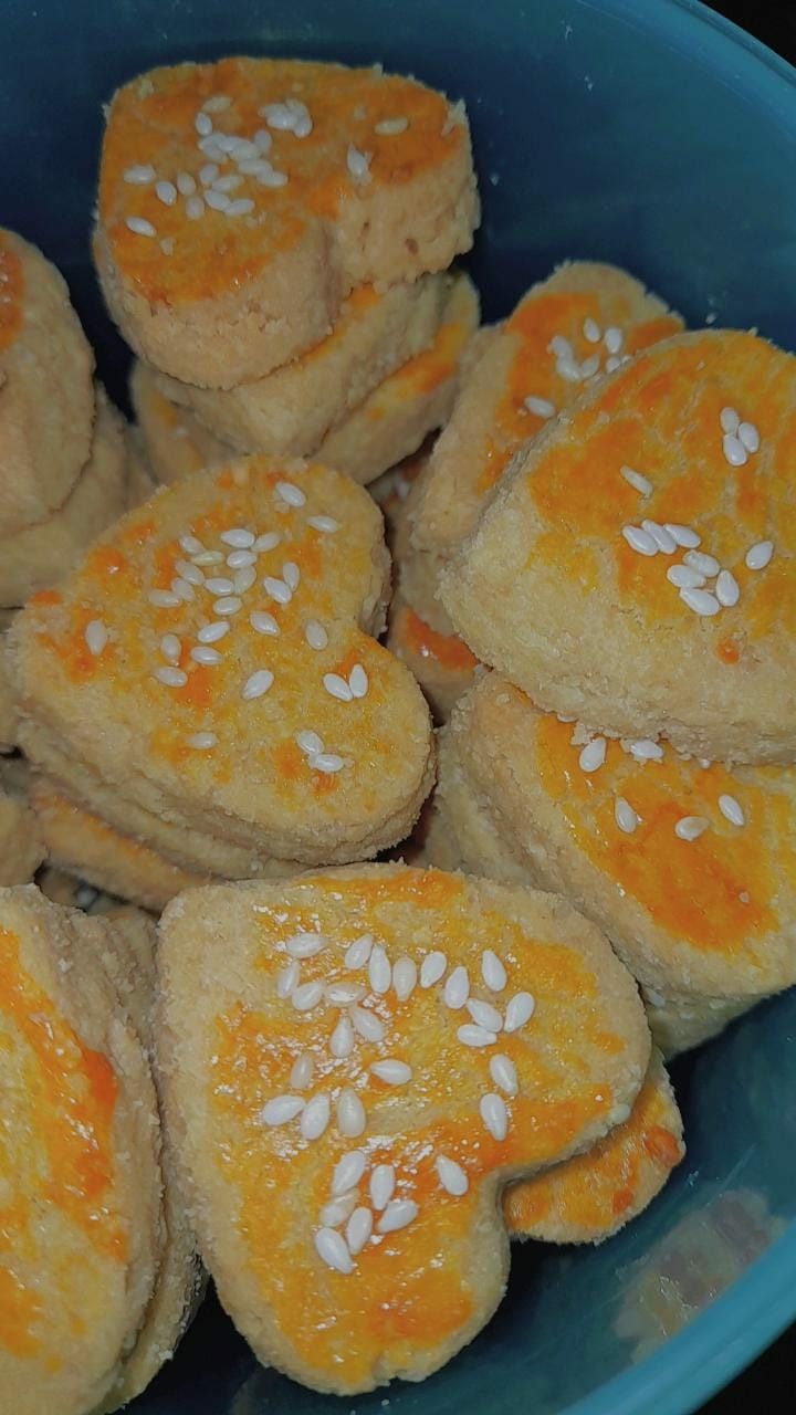 a blue bowl filled with cookies covered in sesame seeds