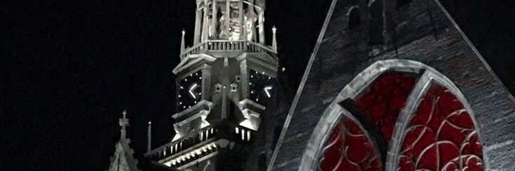 a large clock tower towering over a city at night with red and white designs on it's sides