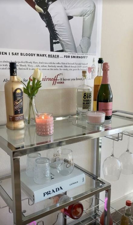 a bar cart with liquor bottles and glasses on it in front of a wall poster