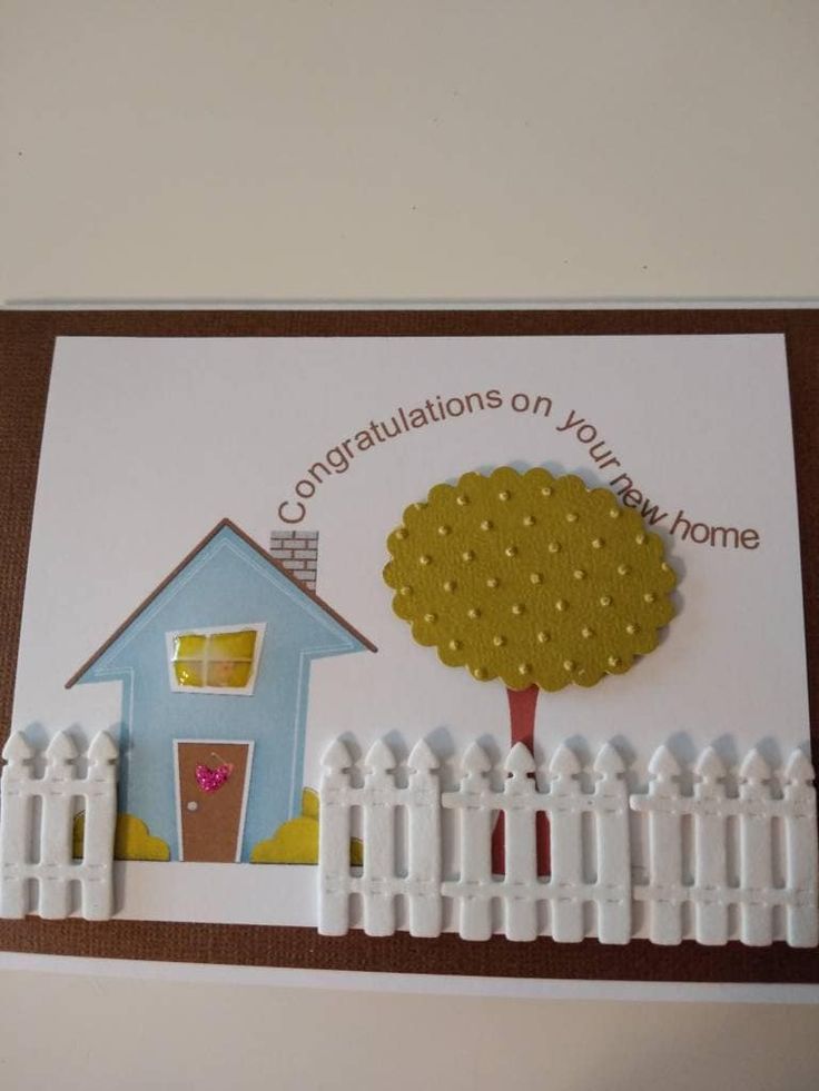 a card with a house and tree on the front, surrounded by white picket fence