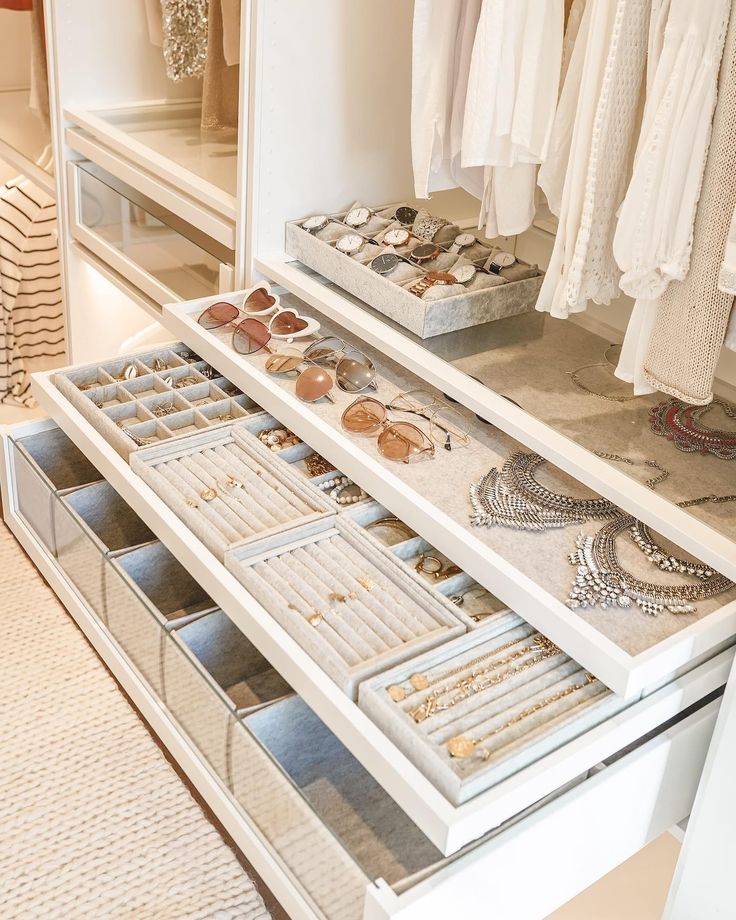 a white closet filled with lots of necklaces and other jewelry on top of drawers