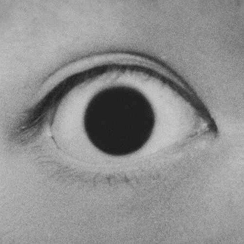 black and white photograph of an eye with the iris partially open to reveal a dark circle