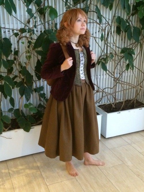 a woman standing in front of a plant with her hand on her hip and looking up