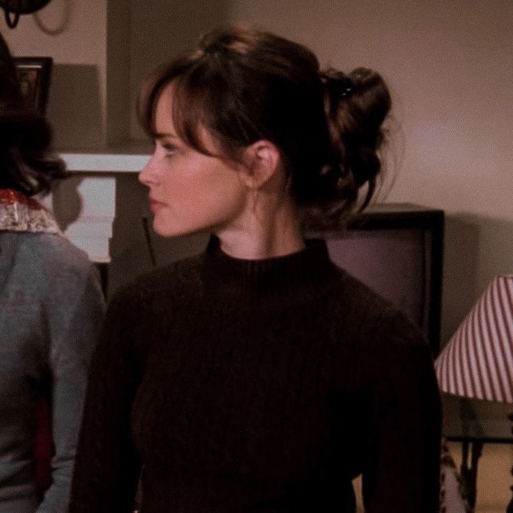 two women standing next to each other in front of a tv screen with one woman wearing a black sweater