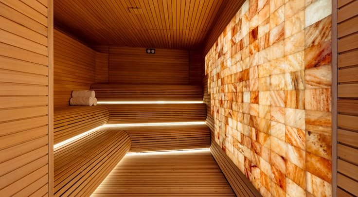 the inside of a wooden sauna with lights shining on the walls and wood flooring