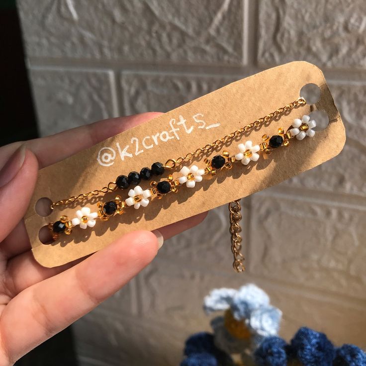 a person holding a piece of jewelry with pearls and black beads on the end of it