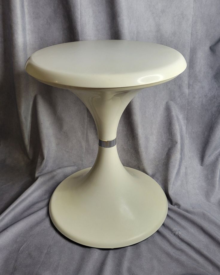 a white cake stand sitting on top of a gray cloth