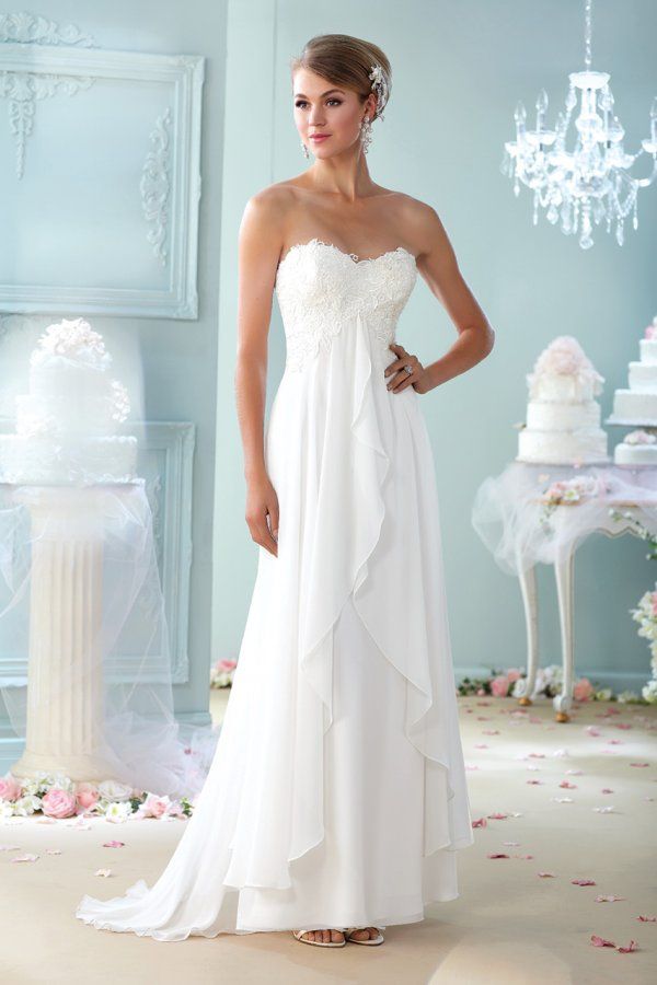 a woman standing in front of a wedding cake wearing a strapless dress with ruffles