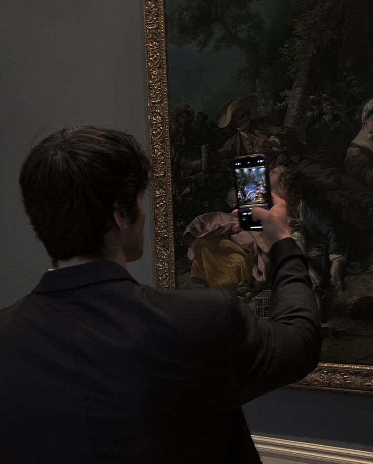 a man taking a photo of a painting with his cell phone in front of him