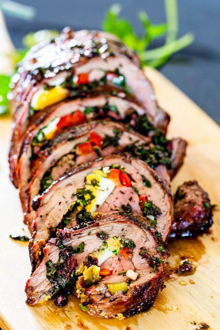 sliced up meat on a cutting board with herbs and seasoning around it's edges