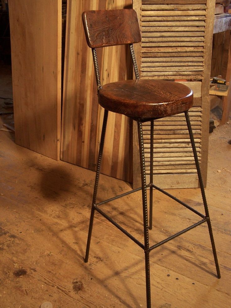 an old fashioned bar stool sitting on top of a hard wood floor next to a wooden wall