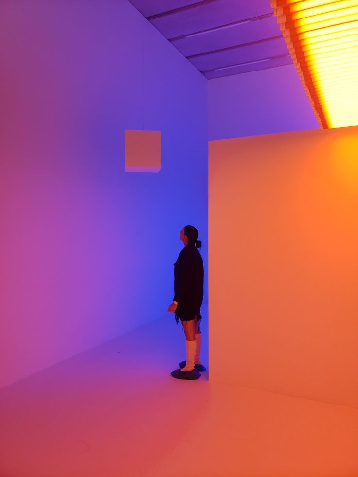 a person standing in an empty room with blue and pink lighting