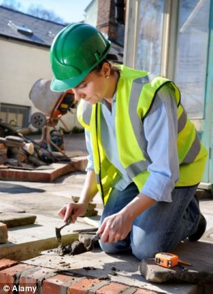 a woman wearing a hard hat and safety vest working on bricks