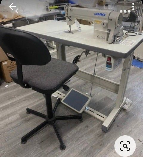 a sewing machine sitting on top of a white table next to a black and gray chair