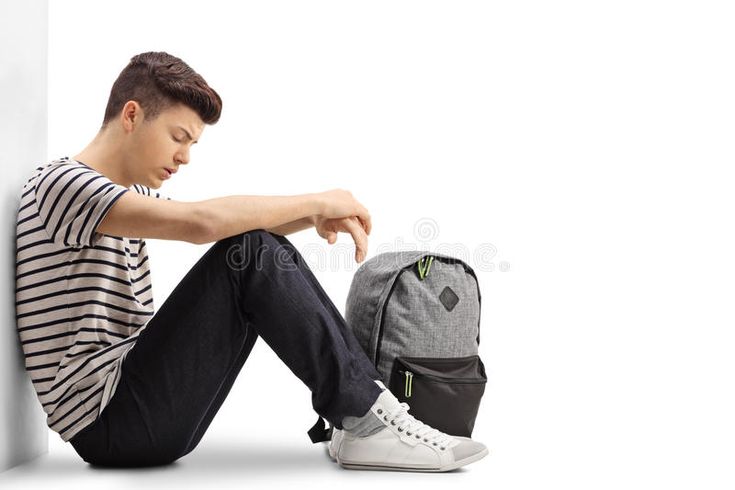 a young man sitting on the floor next to a backpack