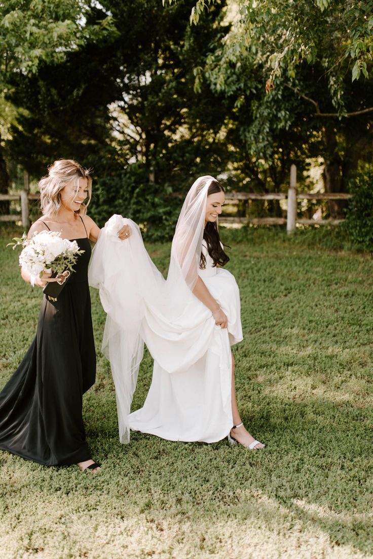 two women in black dresses standing next to each other with veils over their heads