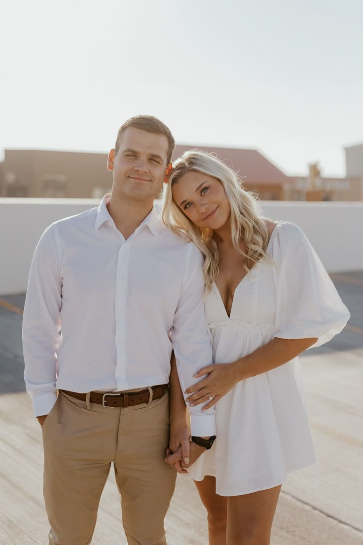 a man and woman standing next to each other in front of a white roof top