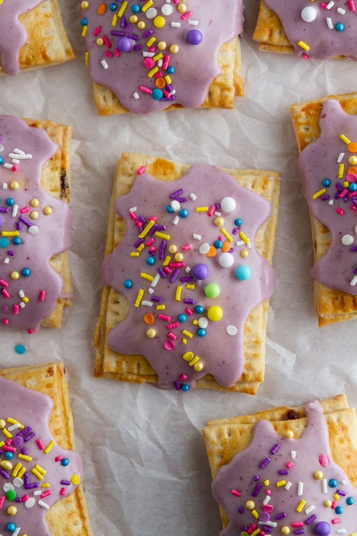 purple frosted desserts with sprinkles on white parchment paper lined up