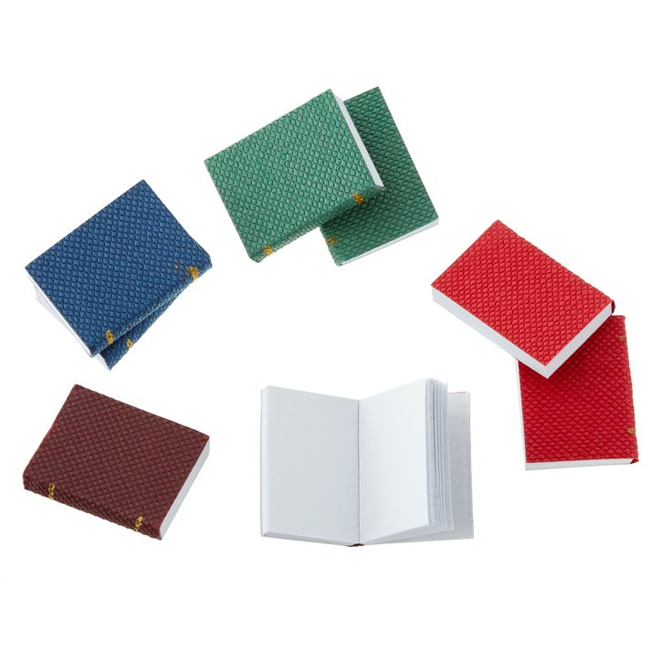 four different colored notebooks sitting next to each other on a white surface with one open book in the middle