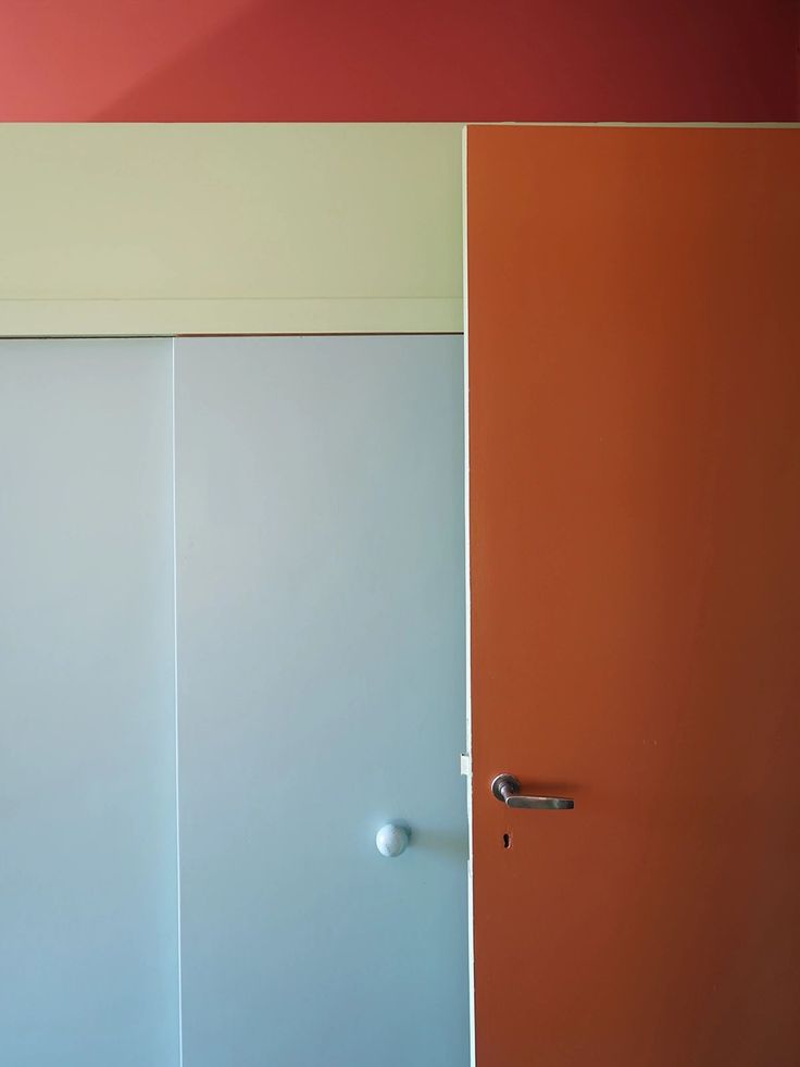 an orange and white door in a room with two doors on each side, one is closed