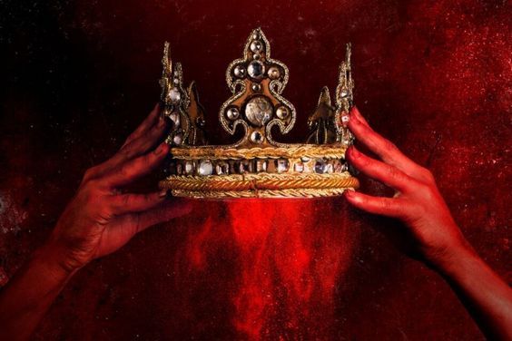 two hands holding up a gold crown against a red background