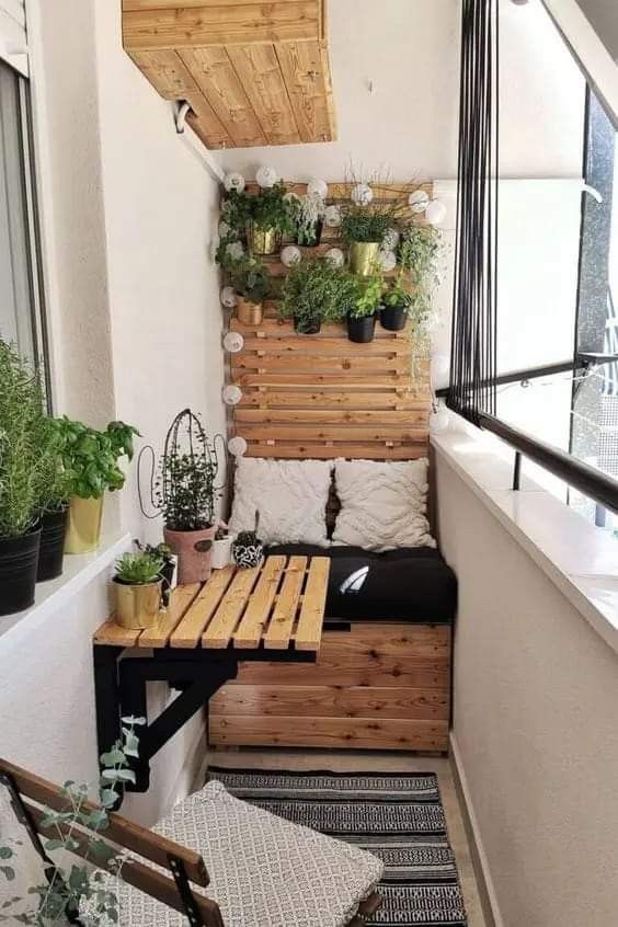 a balcony with plants and potted plants on the wall, along with a bench made out of pallets