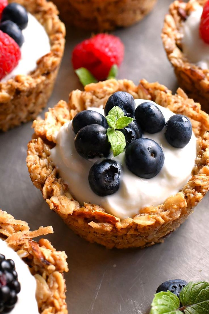 some fruit and yogurt cups are sitting on a silver tray with strawberries, raspberries, and blueberries