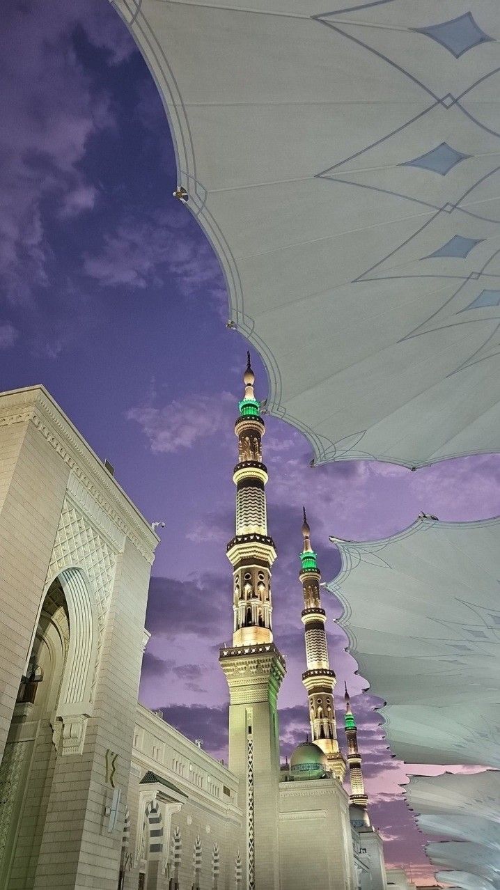 a large white building with two tall towers under an umbrella in front of a purple sky