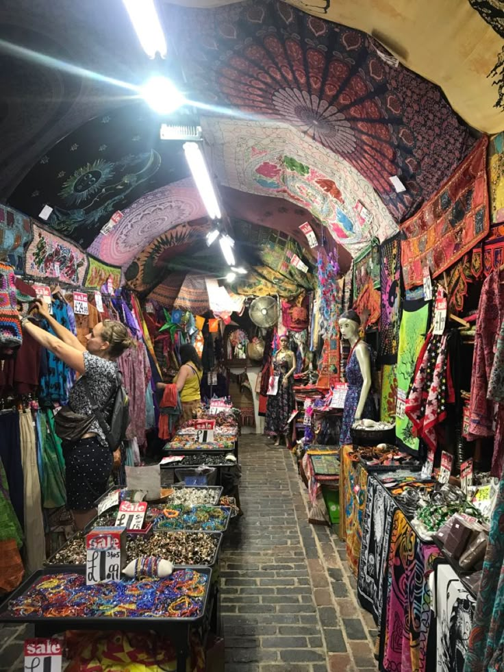 the inside of a market with many items on display and people looking at them in different colors