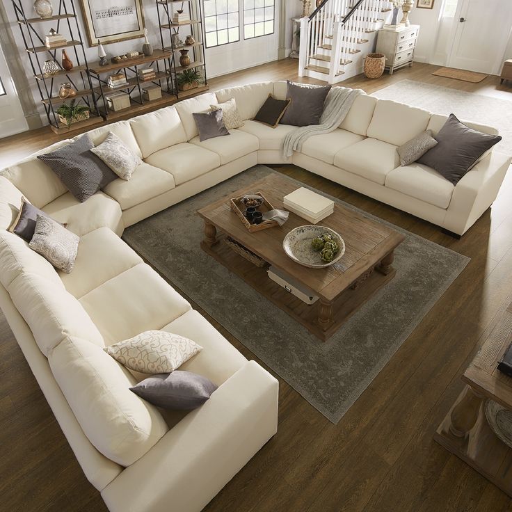 a living room filled with white couches and wooden coffee table in front of a spiral staircase