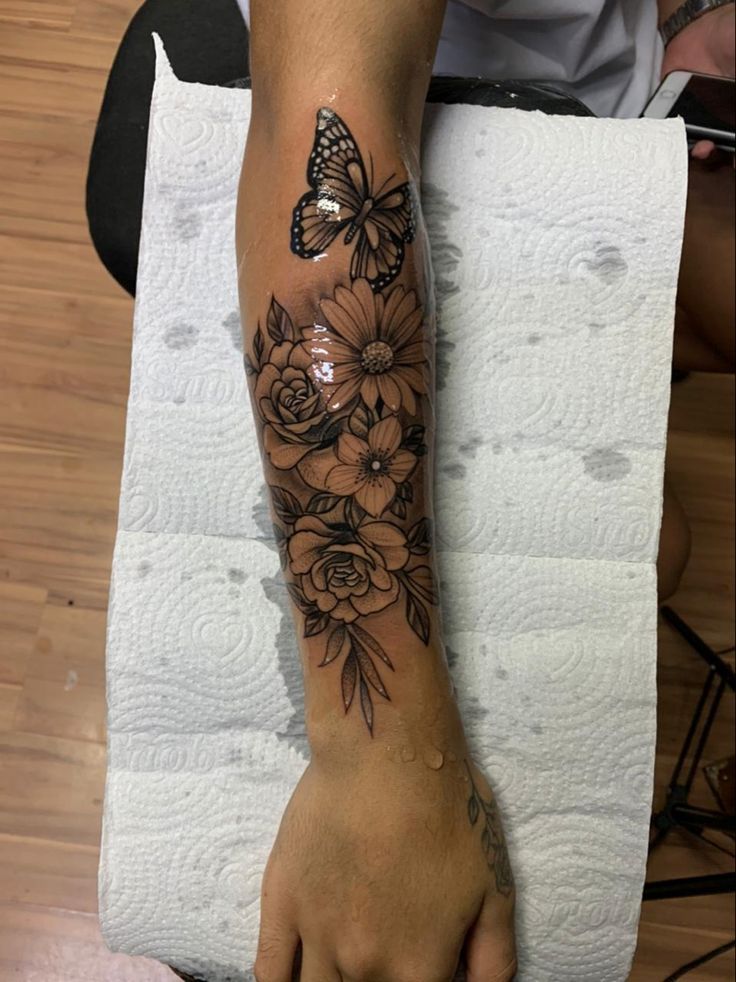 a person with a butterfly and flowers tattoo on their arm